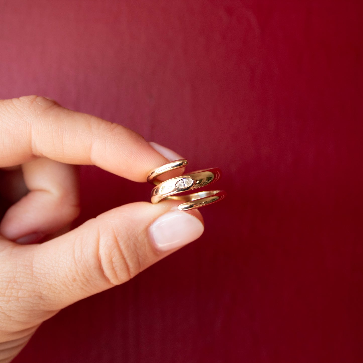 Close-up of a fingers holding a solid 14k yellow gold spiral ring with a lab-grown marquise diamond