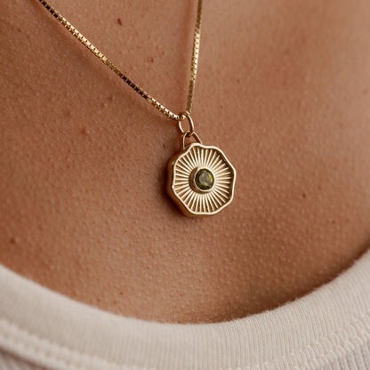 Solid 14k gold pendant with a round bezel-set gemstone being worn