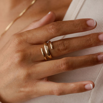 Close-up of a hand wearing 14k solid gold ring with a marquise lab diamond on a neutral background