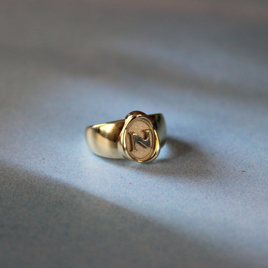 14k gold signet ring resting on a blue surface