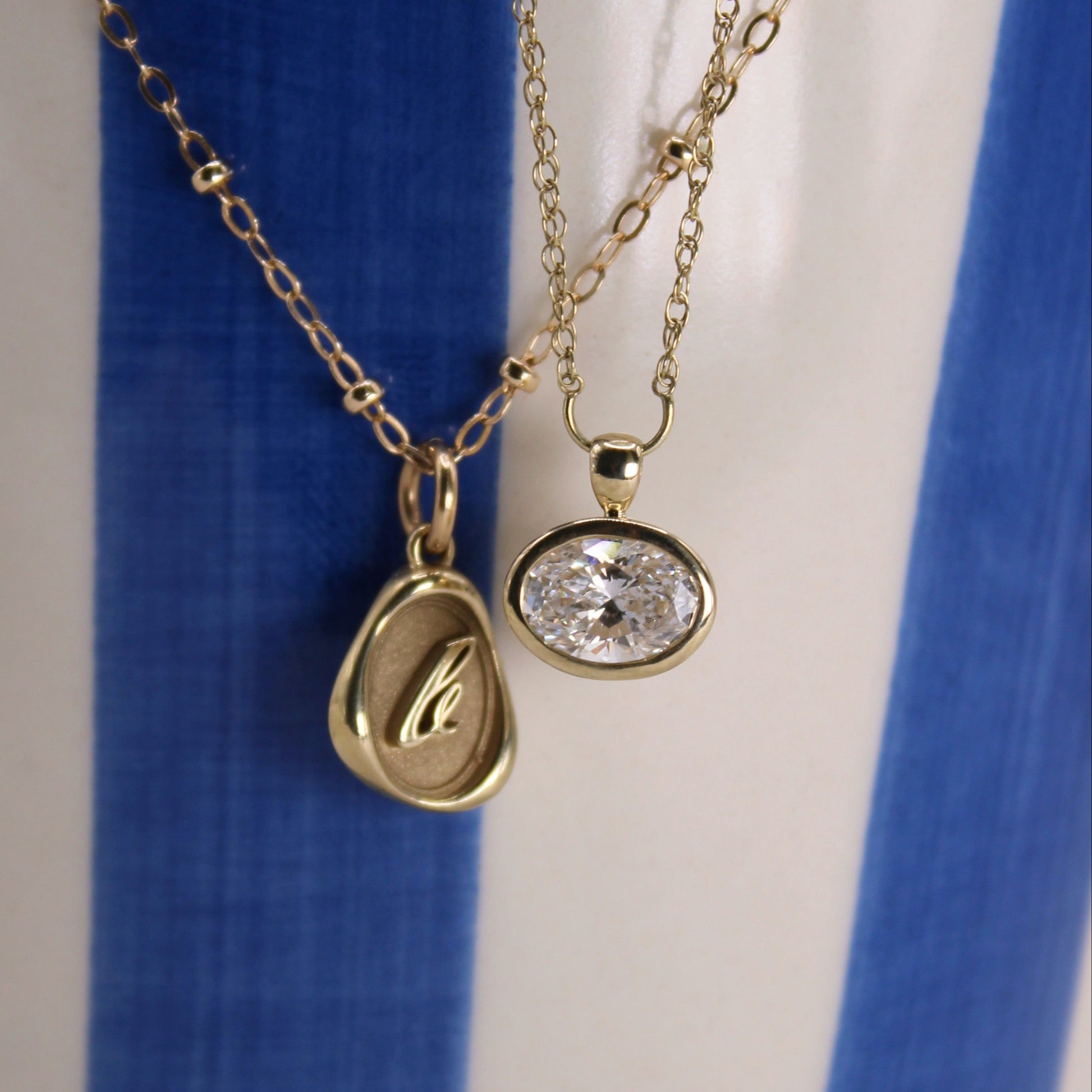 Two gold necklaces with pendants on a blue and white background