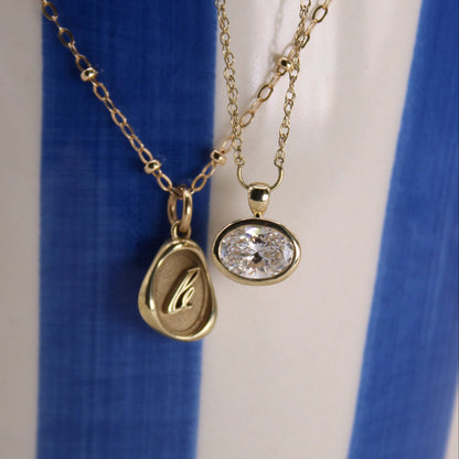 Two gold necklaces with pendants on a blue and white background