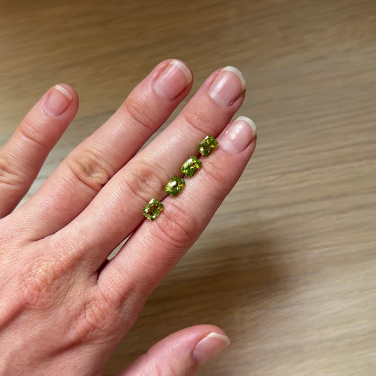 hand with four green peridot gemstones