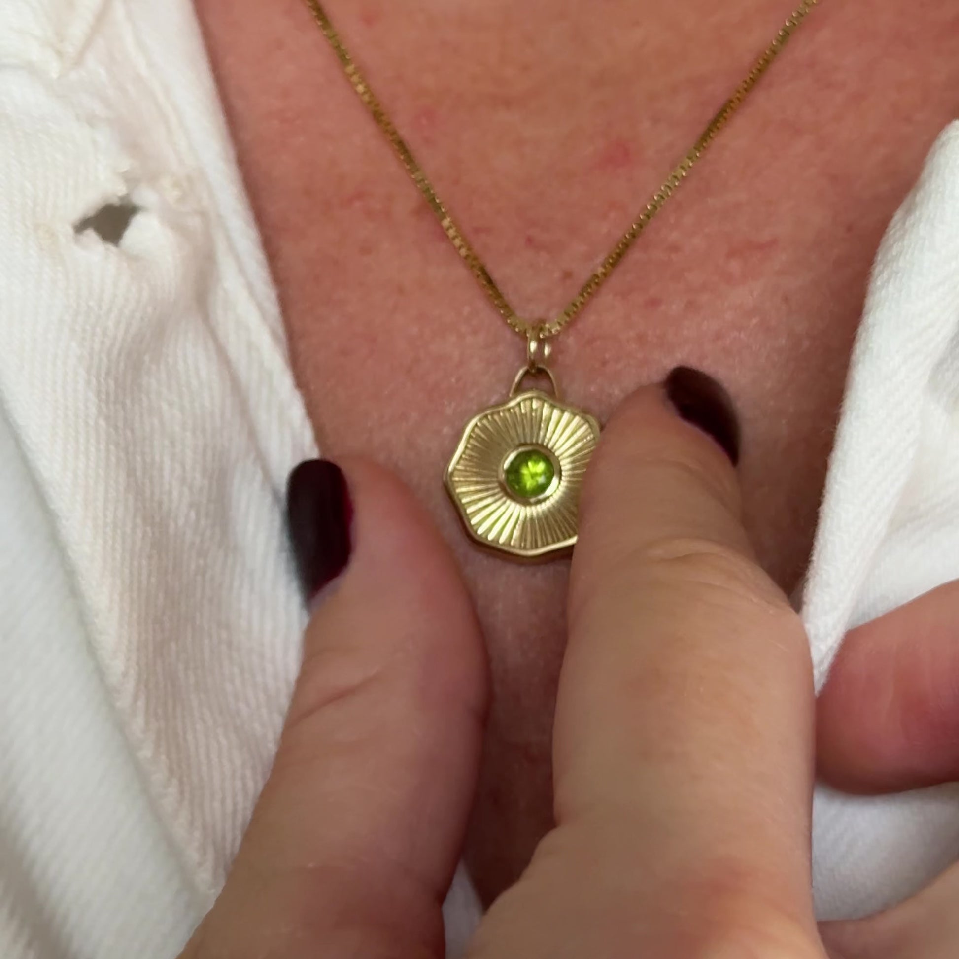 Solid 14k gold necklace with a green gemstone pendant on a chain being worn