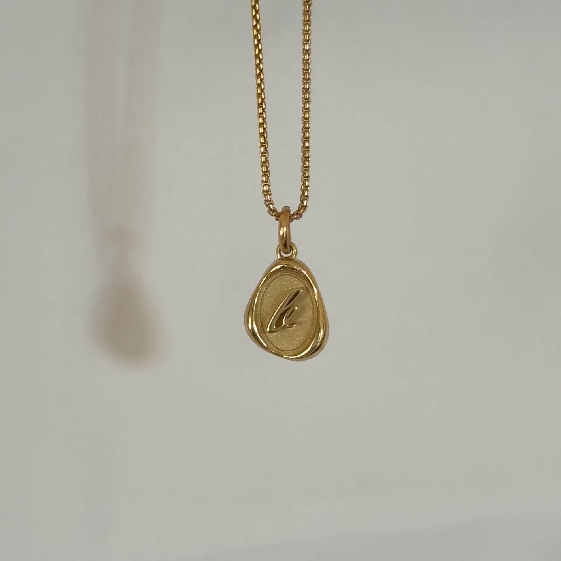 Solid 14k gold charm necklace with custom initial dangling on a chain