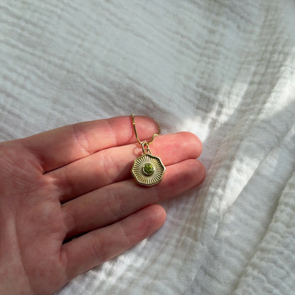 Solid 14k gold necklace with a green gemstone pendant on a cloth background