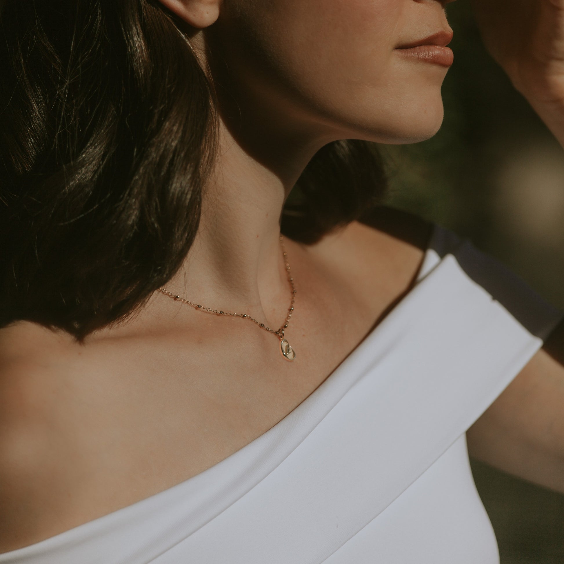 Close-up of a woman wearing a 14k gold necklace with a blurred background